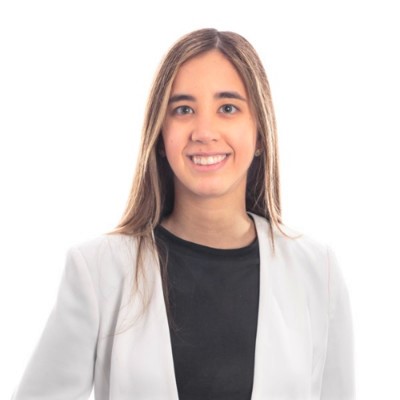 la imagen puede contener a una mujer de cabello castaño claro largo,posando de pie de manera formal y sonriendo un poco. 